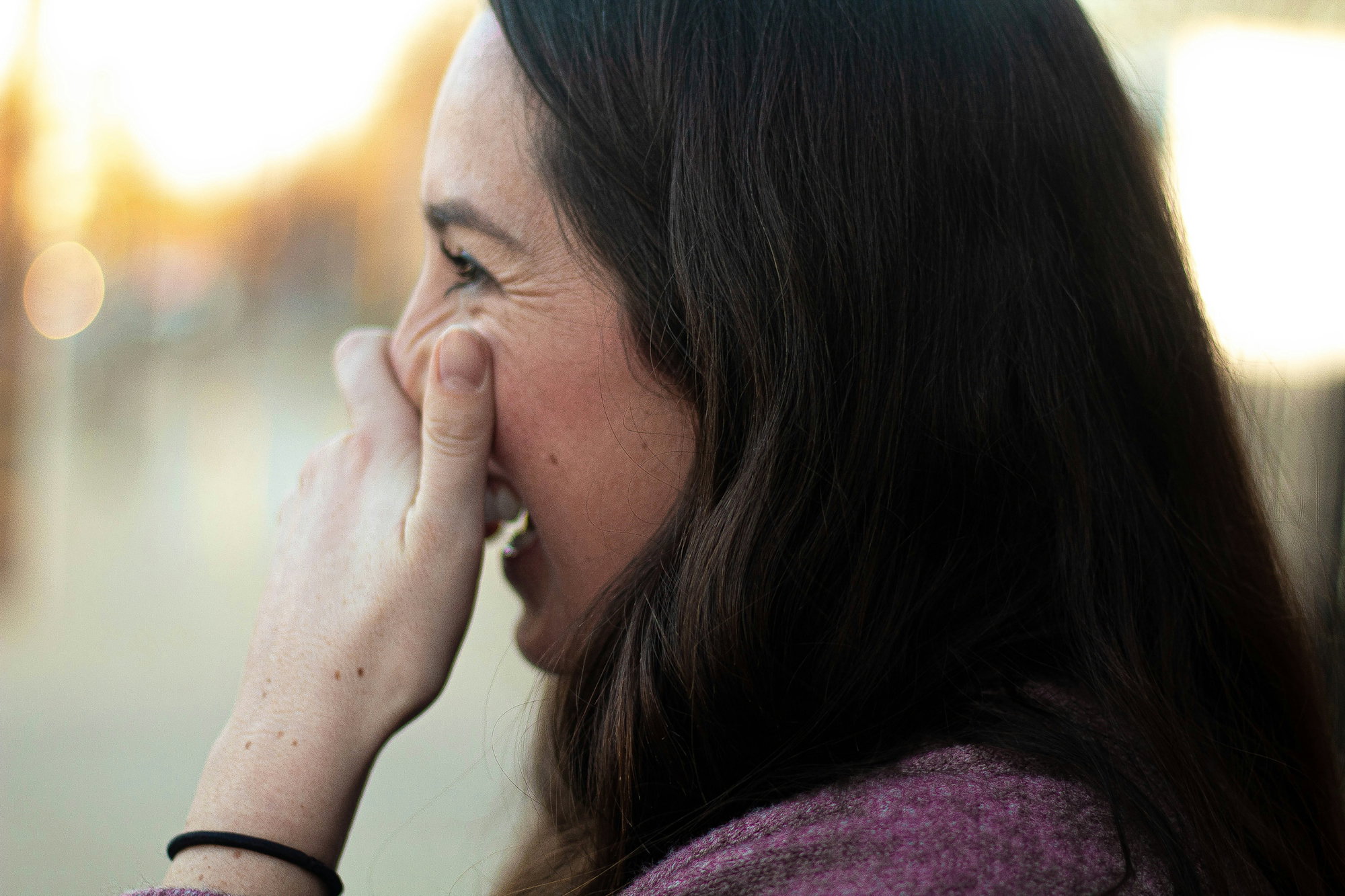 woman covering her nose and mouth while smiling